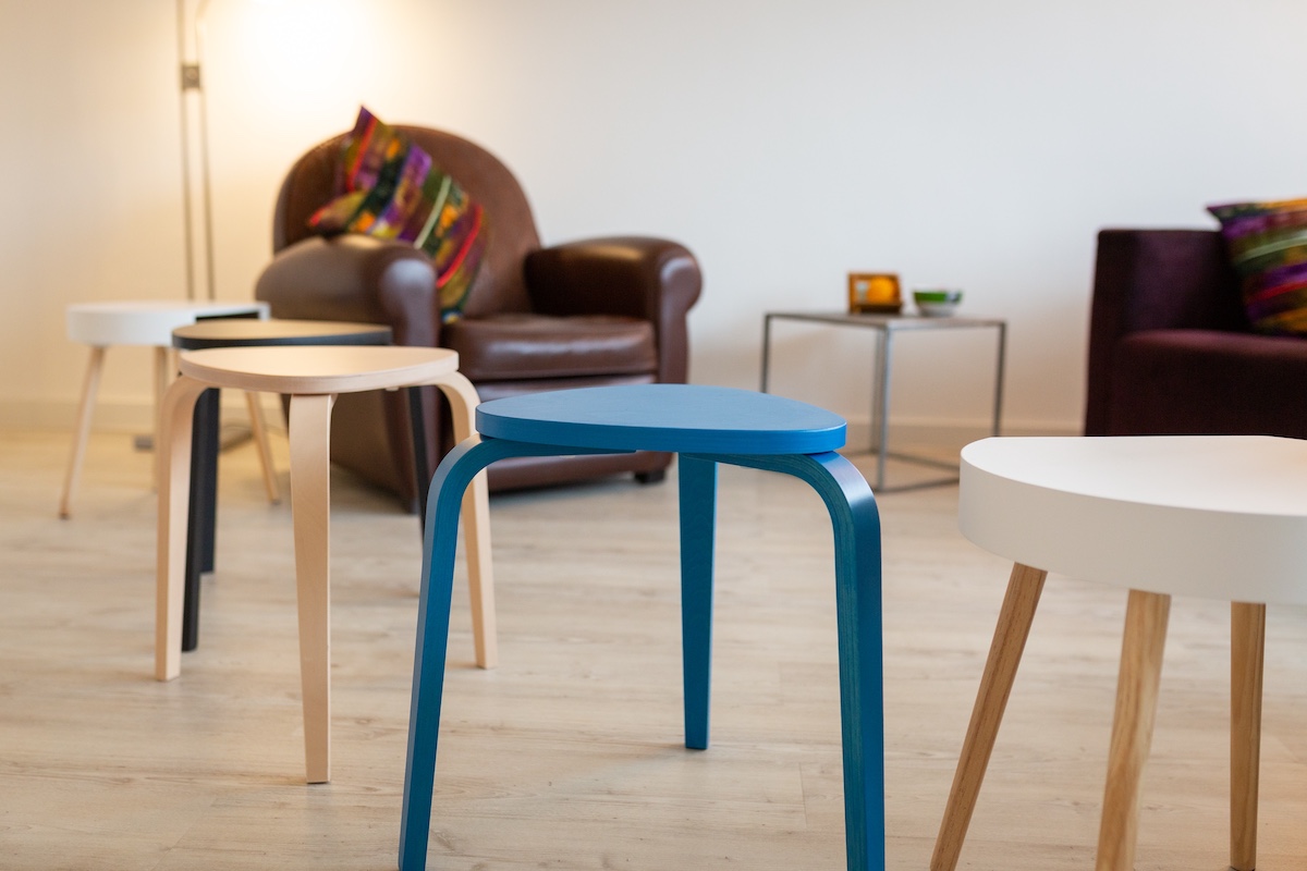 Behandlungsraum 1 – Detailansicht mit farbigen Hockern und Sesseln