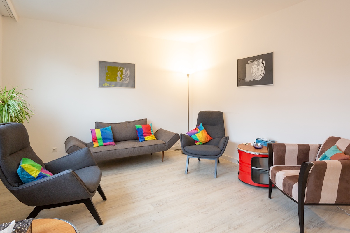 Behandlungsraum 2 – Gesamtansicht mit Sofas, Sesseln und bunten Kissen